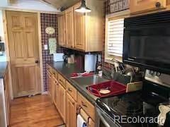81 Gcr 461, Grand Lake, CO 80447 - kitchen featuring black microwave, stainless steel electric stove, dark countertops, light wood-style flooring, and ventilation hood
