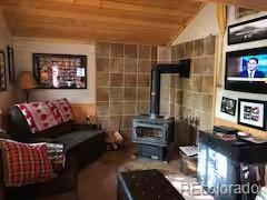 81 Gcr 461, Grand Lake, CO 80447 - living area with wooden ceiling, a wood stove, tile walls, and lofted ceiling