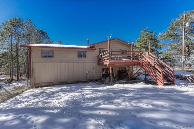 snow covered back of property featuring a wooden deck