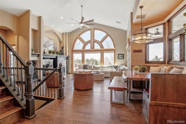 living room with high vaulted ceiling, dark hardwood / wood-style flooring, and ceiling fan with notable chandelier