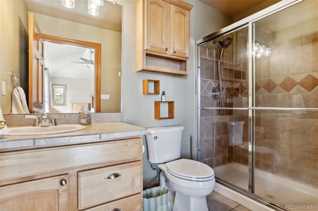 bathroom featuring toilet, ceiling fan, a shower with door, and vanity