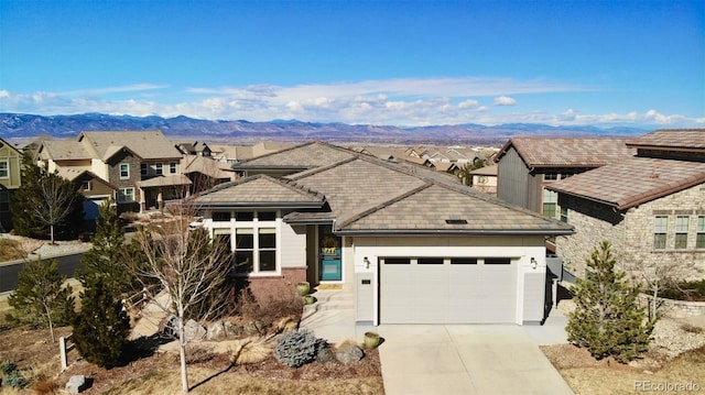 view of front of house with a garage, driveway, a tiled roof, and a mountain view