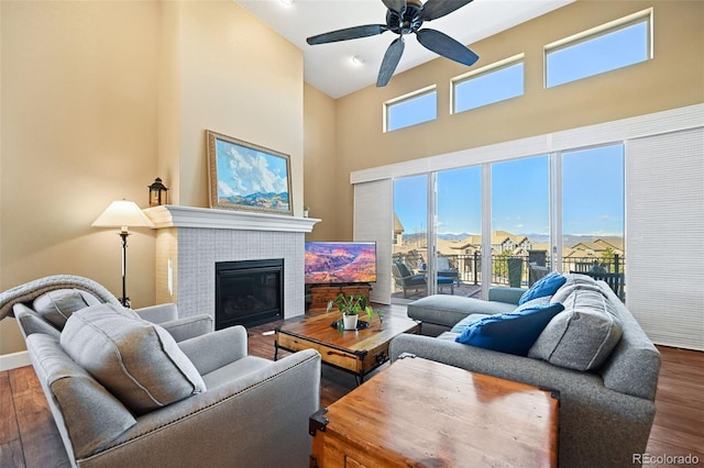 living room featuring a high ceiling, a fireplace, wood finished floors, and a wealth of natural light