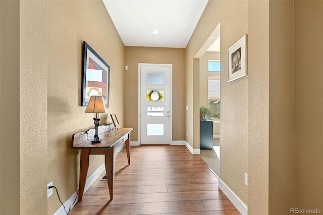 entryway with wood-type flooring, a textured wall, and baseboards