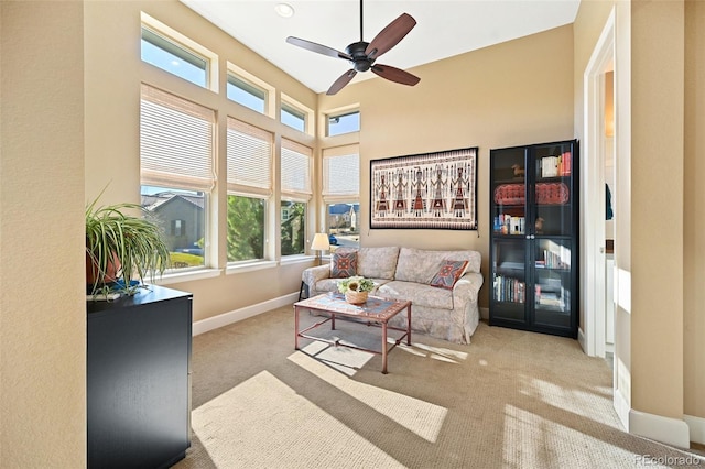 carpeted living room with a high ceiling, baseboards, and a ceiling fan