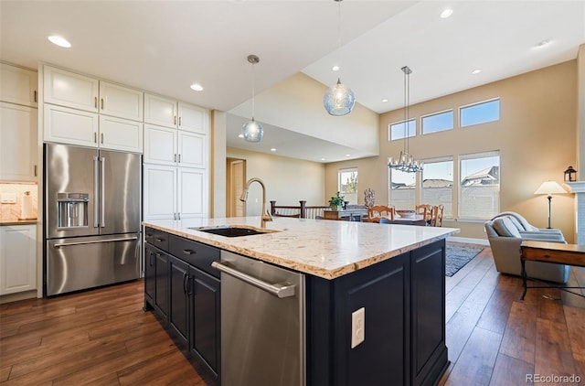 kitchen featuring stainless steel appliances, a sink, white cabinets, dark cabinetry, and dark wood finished floors