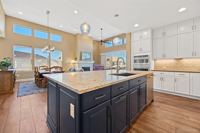 kitchen featuring light wood-style floors, backsplash, white cabinets, and a sink