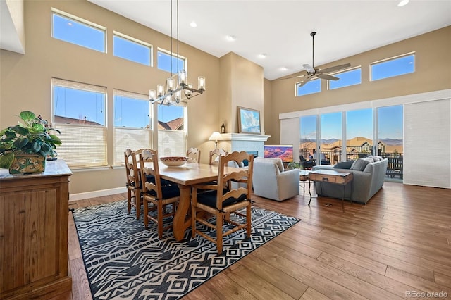 dining area with a towering ceiling, hardwood / wood-style flooring, a fireplace, and a wealth of natural light