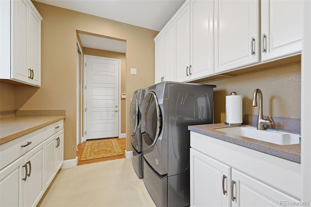 washroom with cabinet space, baseboards, a sink, and independent washer and dryer