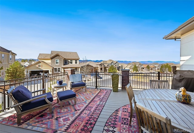 wooden deck featuring a residential view, a mountain view, and grilling area