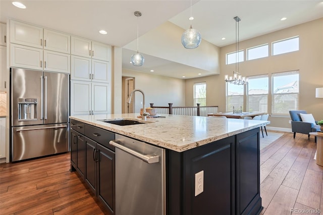 kitchen with wood-type flooring, stainless steel appliances, white cabinetry, and a sink