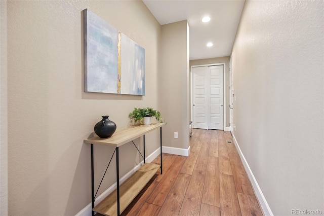 corridor with light wood-style floors, baseboards, and recessed lighting
