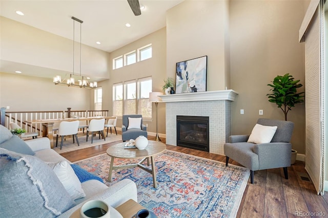 775 Woodgate Dr, Highlands Ranch, CO 80126 - living room featuring a notable chandelier, baseboards, wood finished floors, a tile fireplace, and a high ceiling