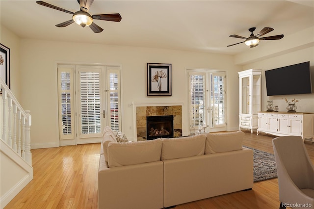 living room featuring a fireplace, ceiling fan, and light wood-type flooring