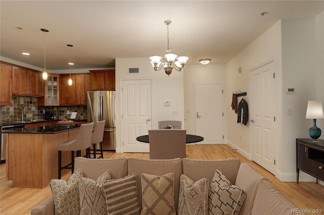 kitchen with pendant lighting, appliances with stainless steel finishes, a center island, tasteful backsplash, and light wood-type flooring