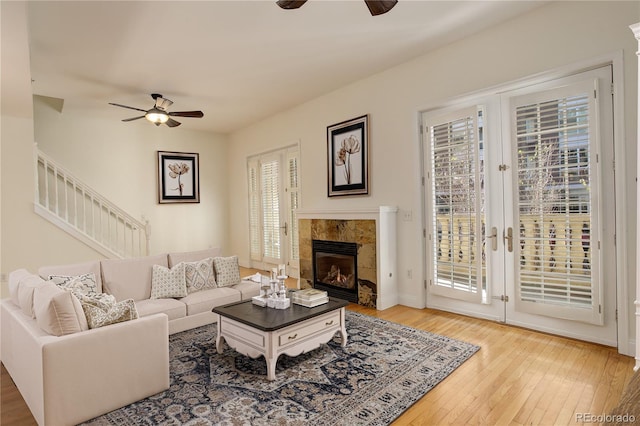 living room featuring hardwood / wood-style flooring, ceiling fan, a tile fireplace, and french doors