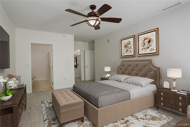 bedroom featuring light carpet, a spacious closet, ceiling fan, and ensuite bathroom