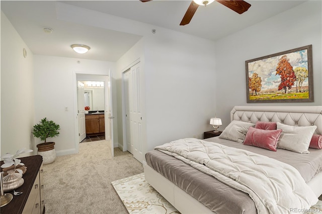 bedroom with ceiling fan, light colored carpet, ensuite bath, and a closet