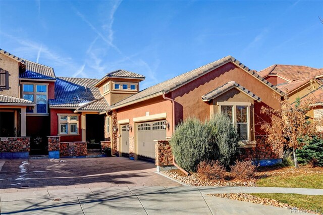 view of front of house with driveway, a tiled roof, an attached garage, and stucco siding