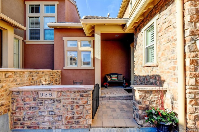 view of exterior entry with stone siding and stucco siding