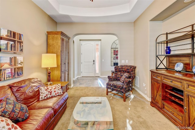 living room with a tray ceiling and light colored carpet