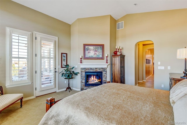 bedroom with light carpet, access to outside, a fireplace, and lofted ceiling