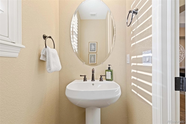 bathroom with a textured wall and a sink