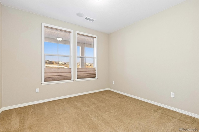 carpeted empty room featuring baseboards and visible vents