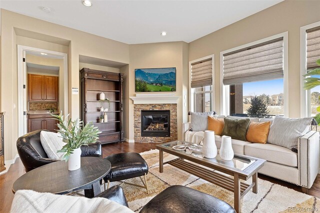 living area featuring baseboards, a stone fireplace, wood finished floors, and recessed lighting