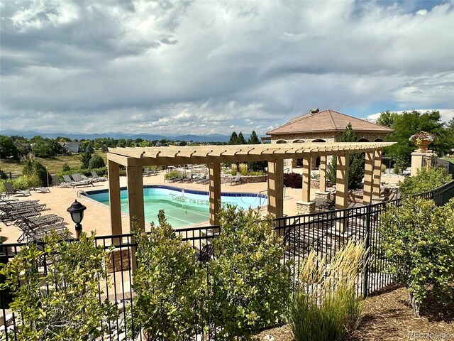 community pool with a patio area, fence, and a pergola