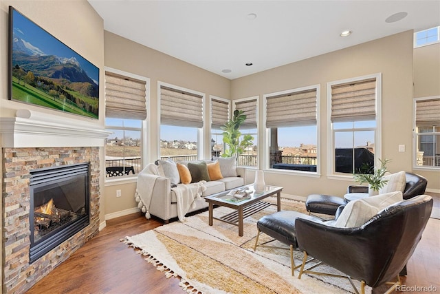 living room featuring a glass covered fireplace, wood finished floors, baseboards, and recessed lighting