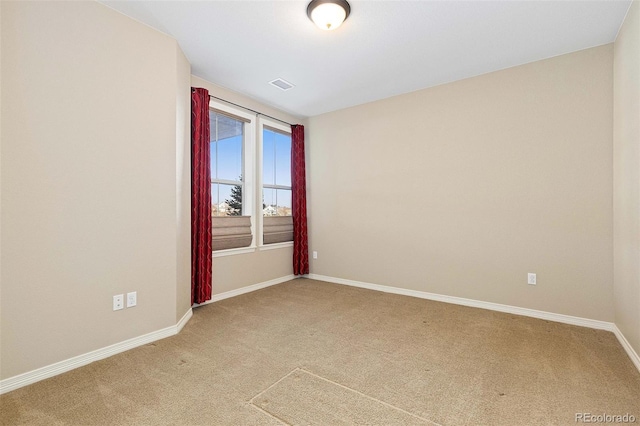 spare room featuring light colored carpet and baseboards