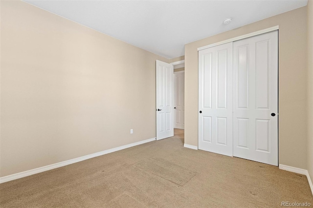 unfurnished bedroom featuring carpet flooring, baseboards, and a closet