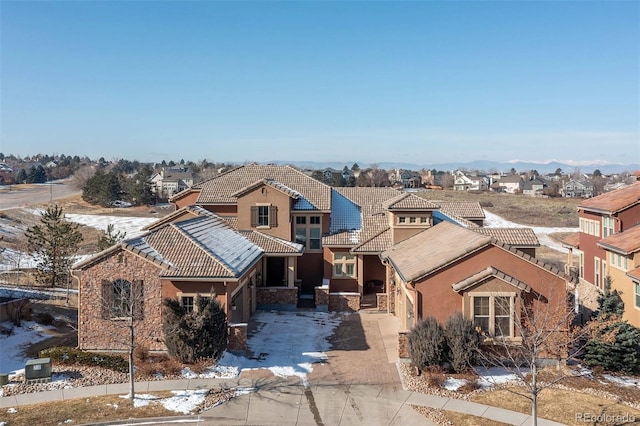 view of front facade with concrete driveway, stucco siding, a tile roof, and a residential view