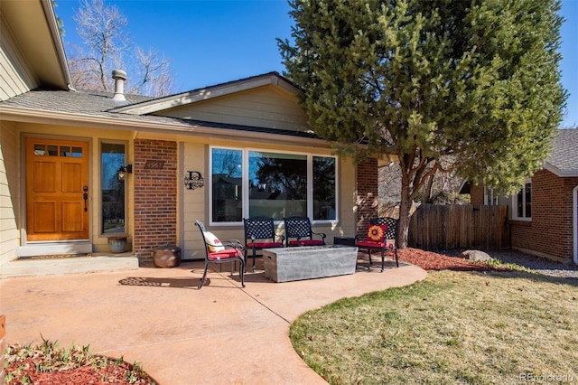 back of property featuring brick siding, fence, roof with shingles, a yard, and a patio
