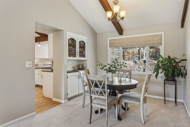 dining space featuring light carpet, vaulted ceiling with beams, baseboards, and a chandelier
