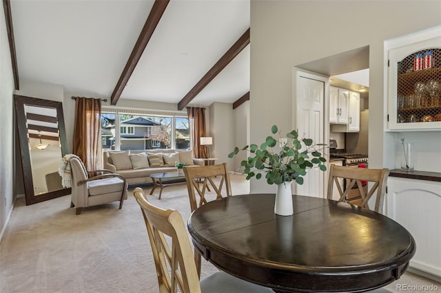 dining area with baseboards, light carpet, and vaulted ceiling with beams