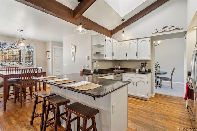 kitchen featuring a sink, open shelves, a kitchen breakfast bar, white cabinetry, and a peninsula