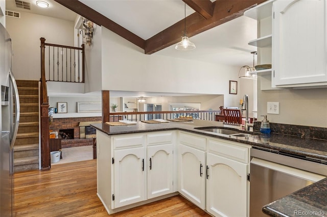 kitchen with visible vents, a sink, stainless steel appliances, white cabinetry, and beamed ceiling