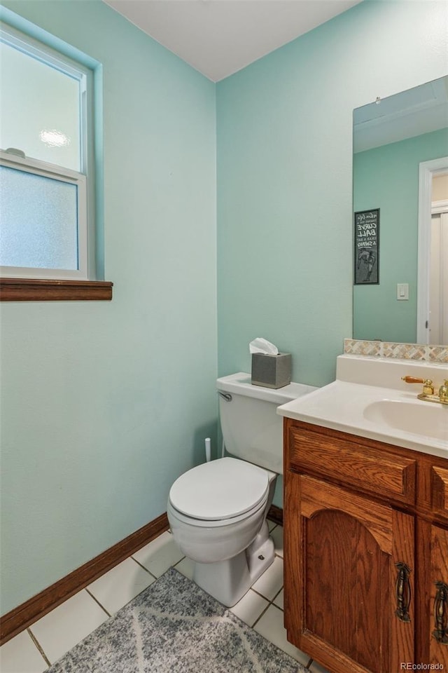 half bath featuring tile patterned flooring, toilet, vanity, and baseboards