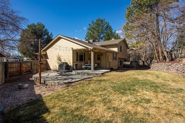 rear view of property featuring a lawn, a fenced backyard, and a patio area