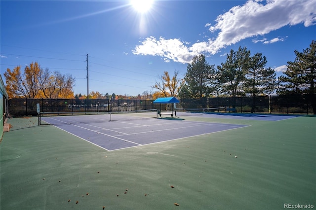 view of tennis court with community basketball court and fence