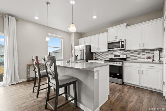 14075 Scarlet Sage St, Parker, CO 80134 - kitchen with stainless steel appliances, backsplash, white cabinetry, dark wood finished floors, and recessed lighting