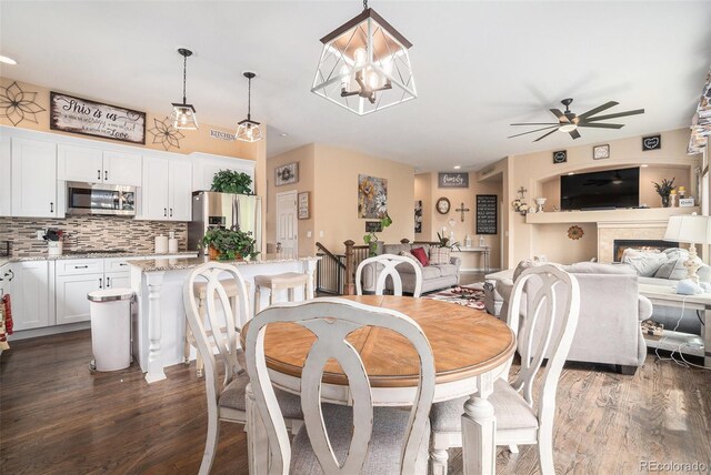 2726 Aylesbury Way, Johnstown, CO 80534 - dining space featuring a ceiling fan, dark wood-style floors, a fireplace, and a chandelier