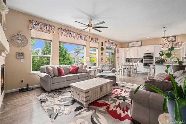 2726 Aylesbury Way, Johnstown, CO 80534 - living area with a ceiling fan, baseboards, light wood-style floors, and a fireplace