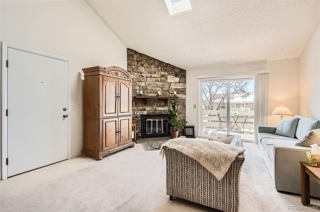 living area featuring a textured ceiling, high vaulted ceiling, a stone fireplace, light carpet, and a skylight