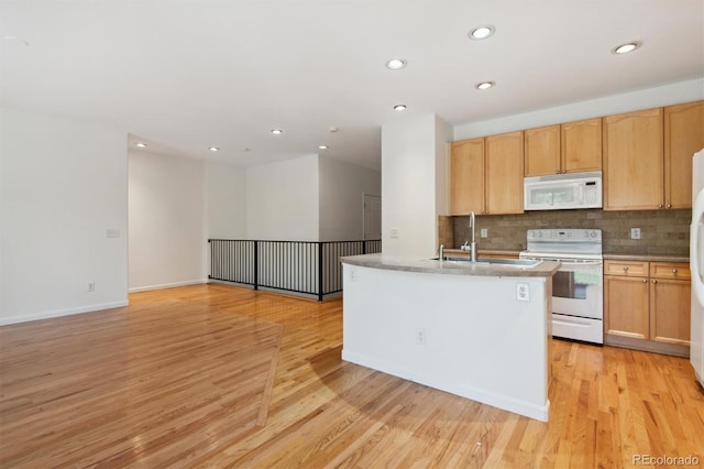 kitchen with white appliances, light hardwood / wood-style floors, an island with sink, sink, and light brown cabinets