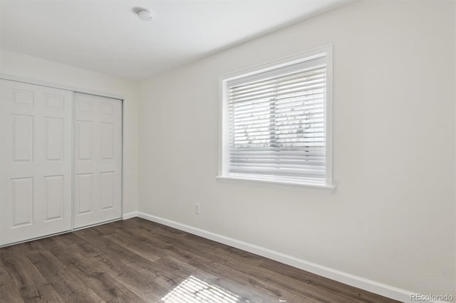 unfurnished bedroom with dark hardwood / wood-style flooring and a closet