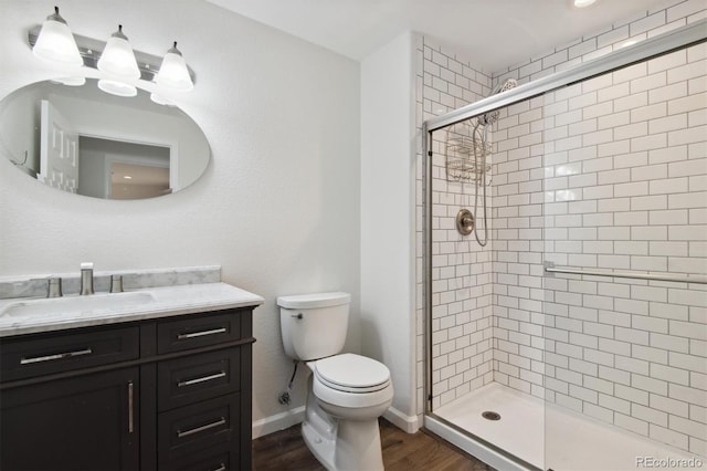 bathroom featuring hardwood / wood-style floors, vanity, toilet, and a shower with shower door