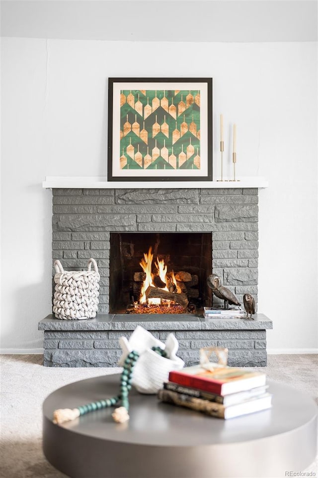 detailed view of a brick fireplace, carpet flooring, and baseboards
